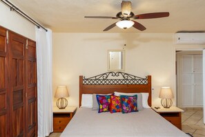 A bedroom with a wooden bed, two bedside lamps, a ceiling fan, and a wardrobe. - Ocean Front/Heated Pool, 6 Adults+ 2 kids under 12 (Puerto Vallarta)