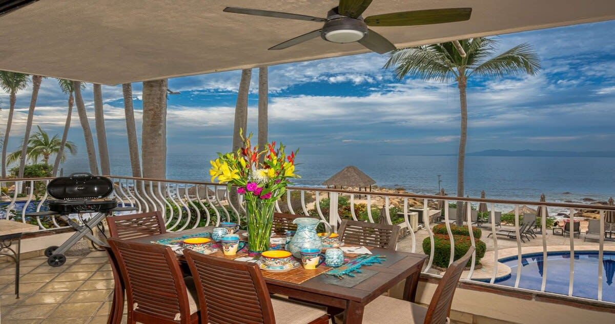 Un balcon avec une table dressée pour les repas, un barbecue et une vue sur l’océan.