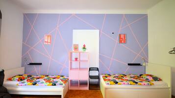 Una habitación con dos camas, un escritorio pequeño y una silla.