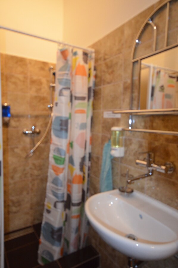A bathroom with a shower, a sink, and a mirror. - Travel & Joy backpackers (Prague)