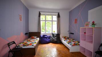 A room with two single beds, a window, a desk, and a chair.
