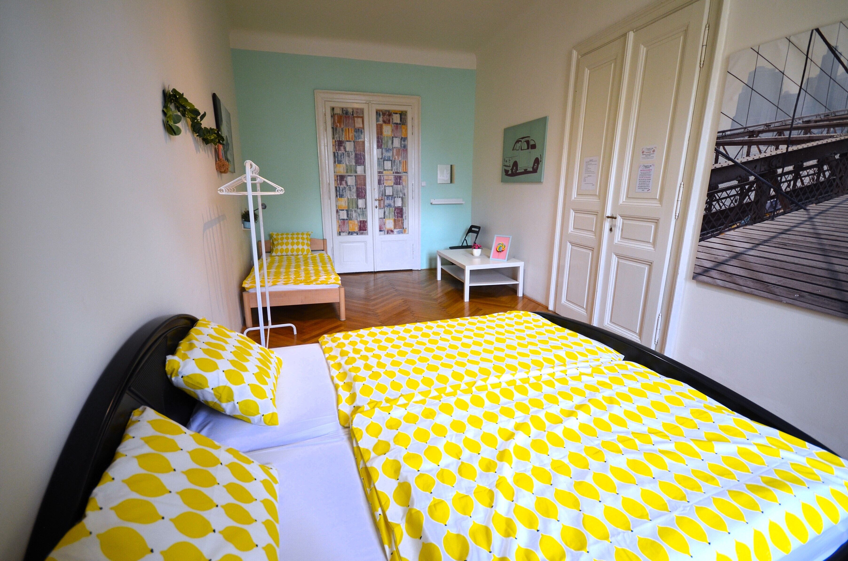 Een kamer met twee bedden, een stoel, een tafel en een deur met een raam.