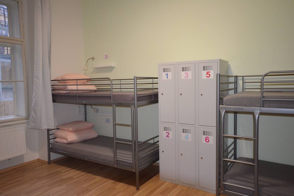 Bunk beds with lockers, a window with a curtain, and a radiator.