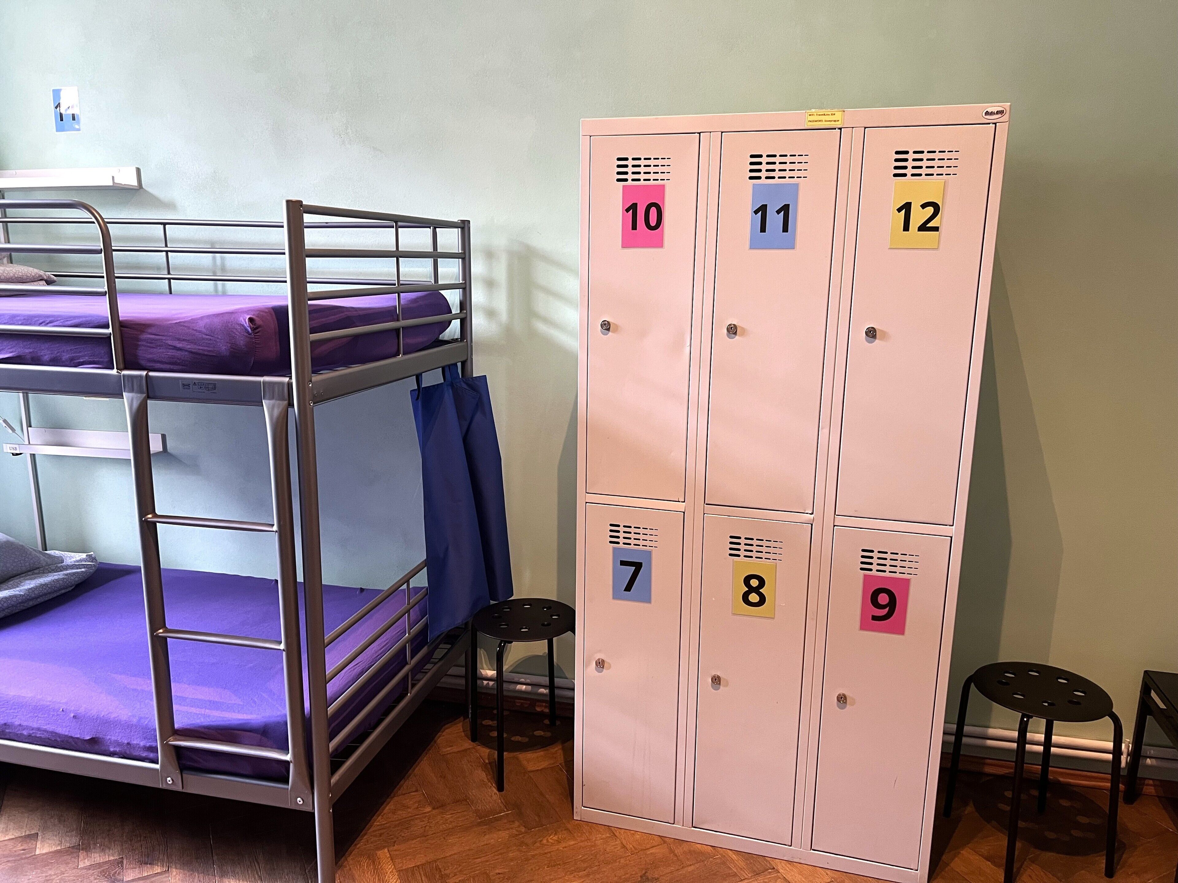 Bunk beds with purple bedding, a set of lockers numbered 7 to 12, and two small stools.