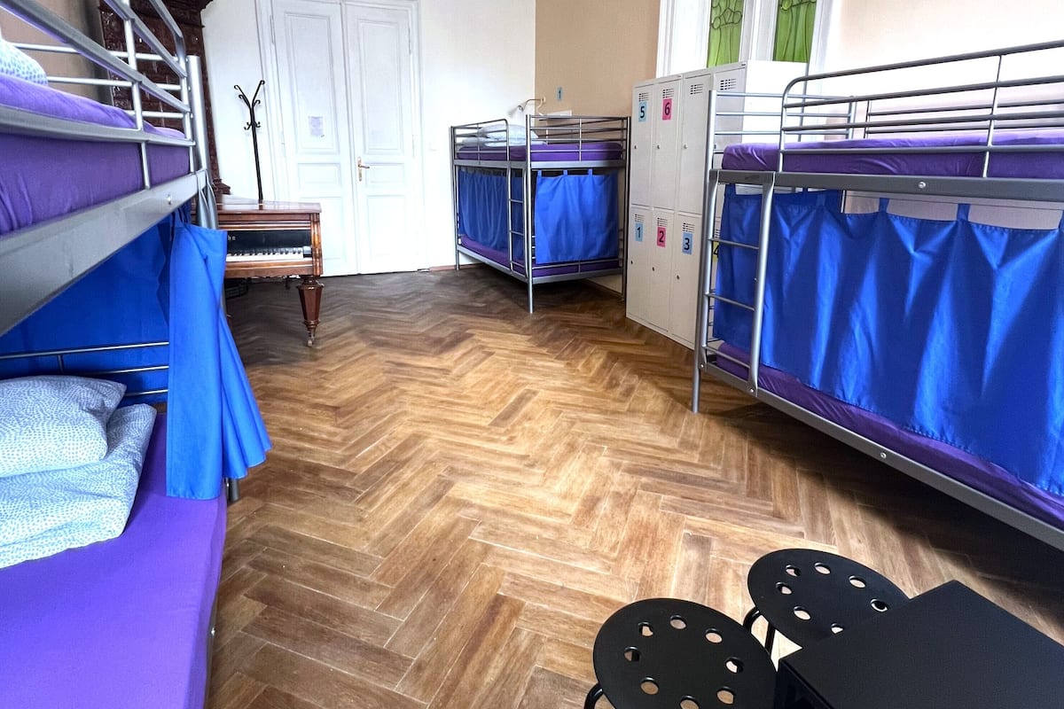 A dormitory room with bunk beds, a piano, a table, and chairs.