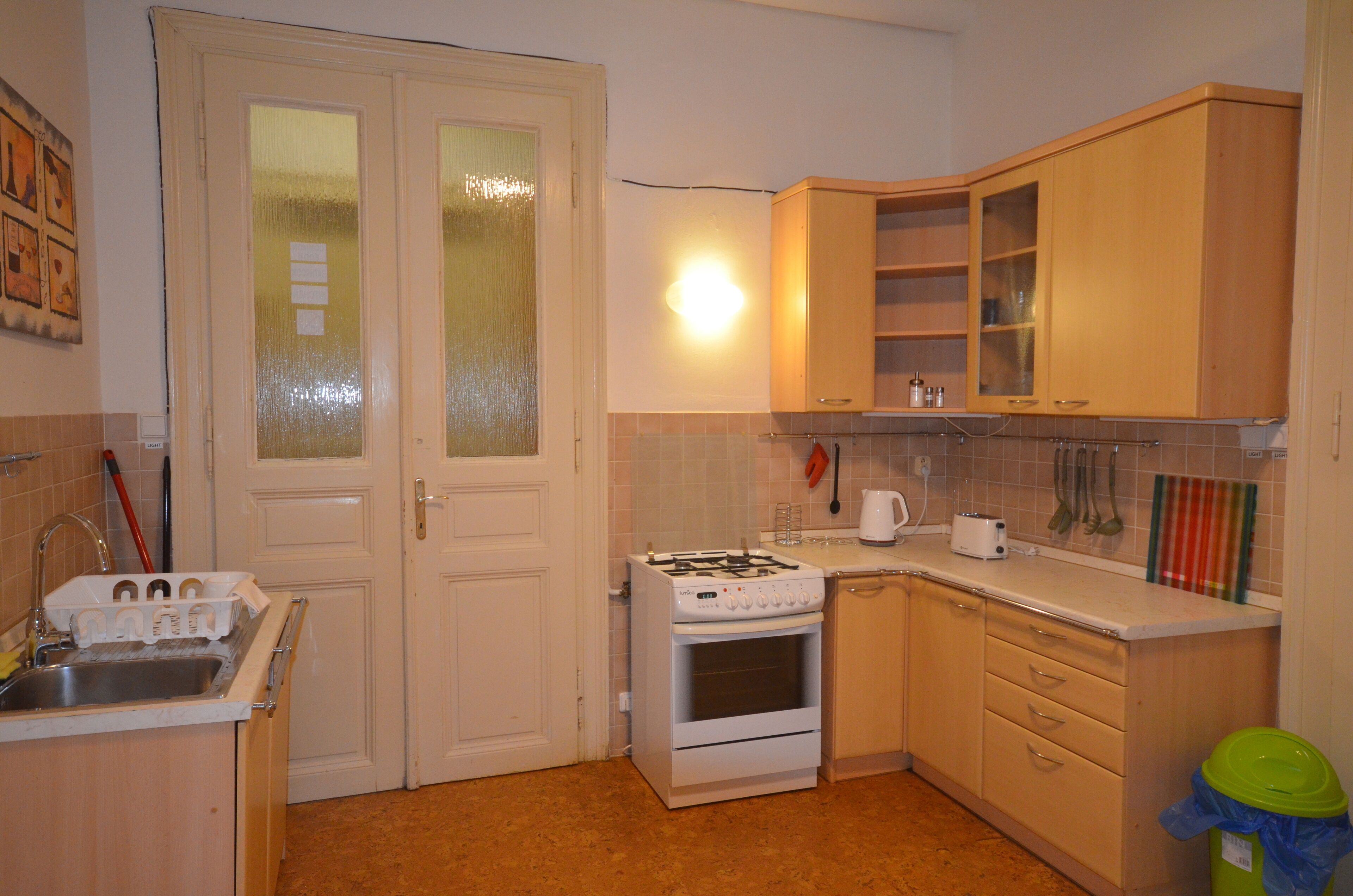 A compact kitchen with a gas stove, oven, and a sink. There are cabinets and a countertop with various items.