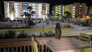 En utomhusplats med bord och stolar, en dekorativ uggleskulptur och utsikt över ett hotell med flera byggnader och en parkeringsplats.