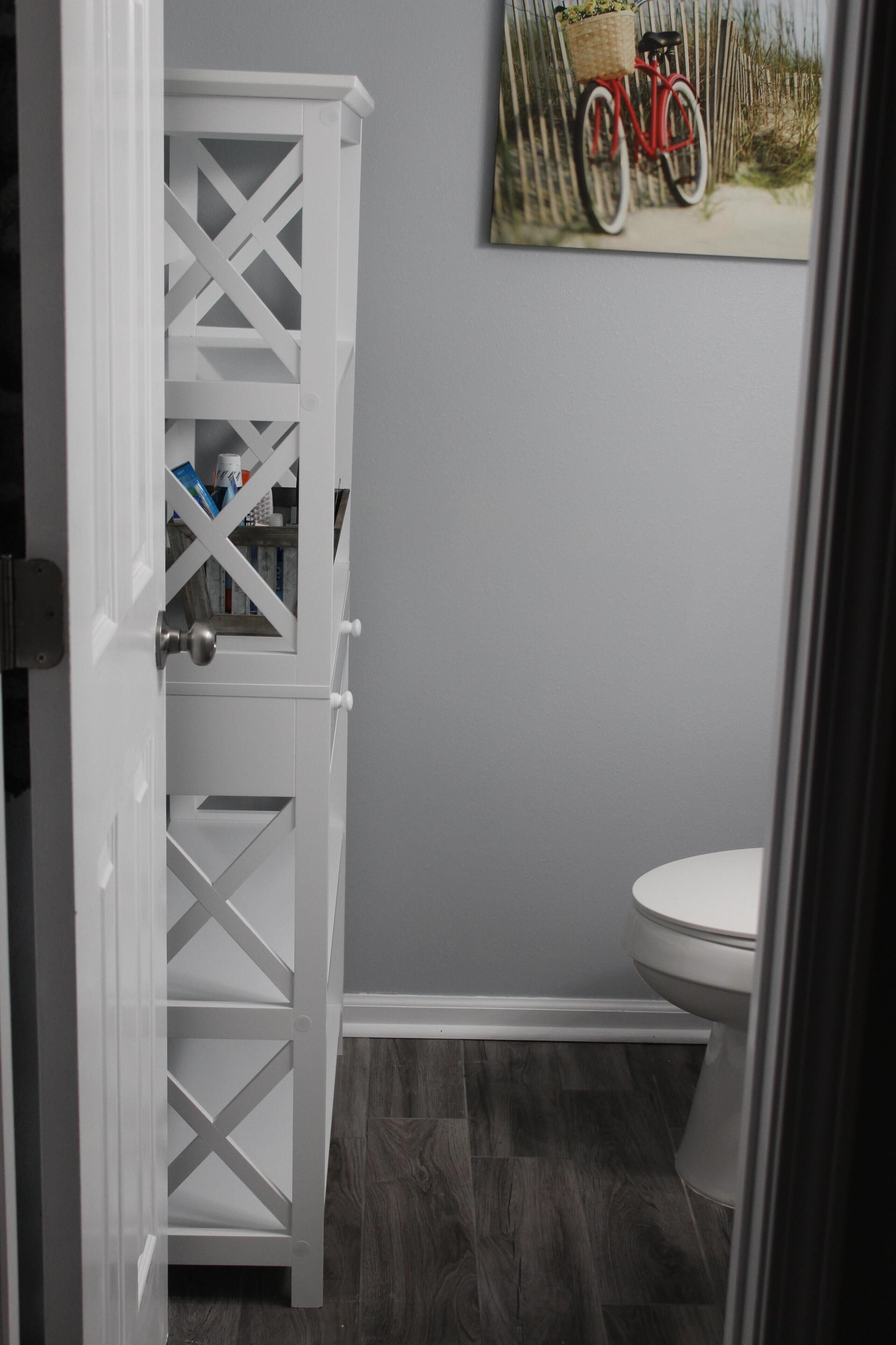 A bathroom with a white door, a toilet, and a wall-mounted picture of a bicycle.