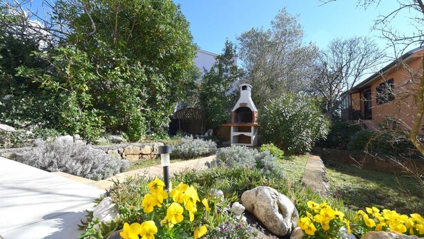 A stone patio with a brick oven, surrounded by various plants and flowers. - Apartment Klara 1 on the ground floor (Krk)