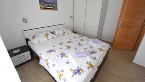 A bedroom with a bed, a nightstand, a wardrobe, and a door. - Apartment Klara 1 on the ground floor (Krk)