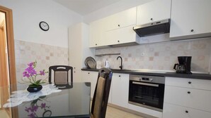 A modern kitchen with white cabinets, a black countertop, a built-in oven, and a coffee maker. - Apartment Klara 1 on the ground floor (Krk)
