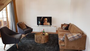 Un salon moderne avec un téléviseur, deux canapés, une table basse et une grande fenêtre.