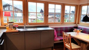 Une cuisine avec des meubles en bois, un évier et une fenêtre donnant sur un village.