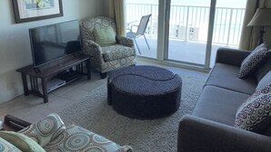Un salon comprenant un canapé, un pouf et un fauteuil, une télévision et une décoration en forme d’étoile accrochée au mur.