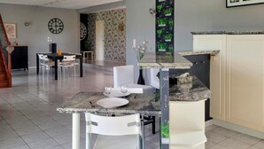 A modern kitchen with a marble countertop, white chairs, and a dining table. - 3 bedroom cozy home in Quarante (Quarante)