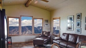 Un salon avec vue sur les montagnes, doté d’un ventilateur de plafond et d’une cheminée.
