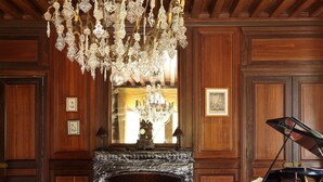 Una sala espaiosa amb un gran candelabrum, un piano de cua i una llar de foc.