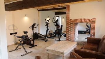 A home gym with exercise equipment, a wooden coffee table, and leather furniture.