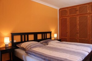 A bedroom with a bed, two bedside tables, and a wooden wardrobe.