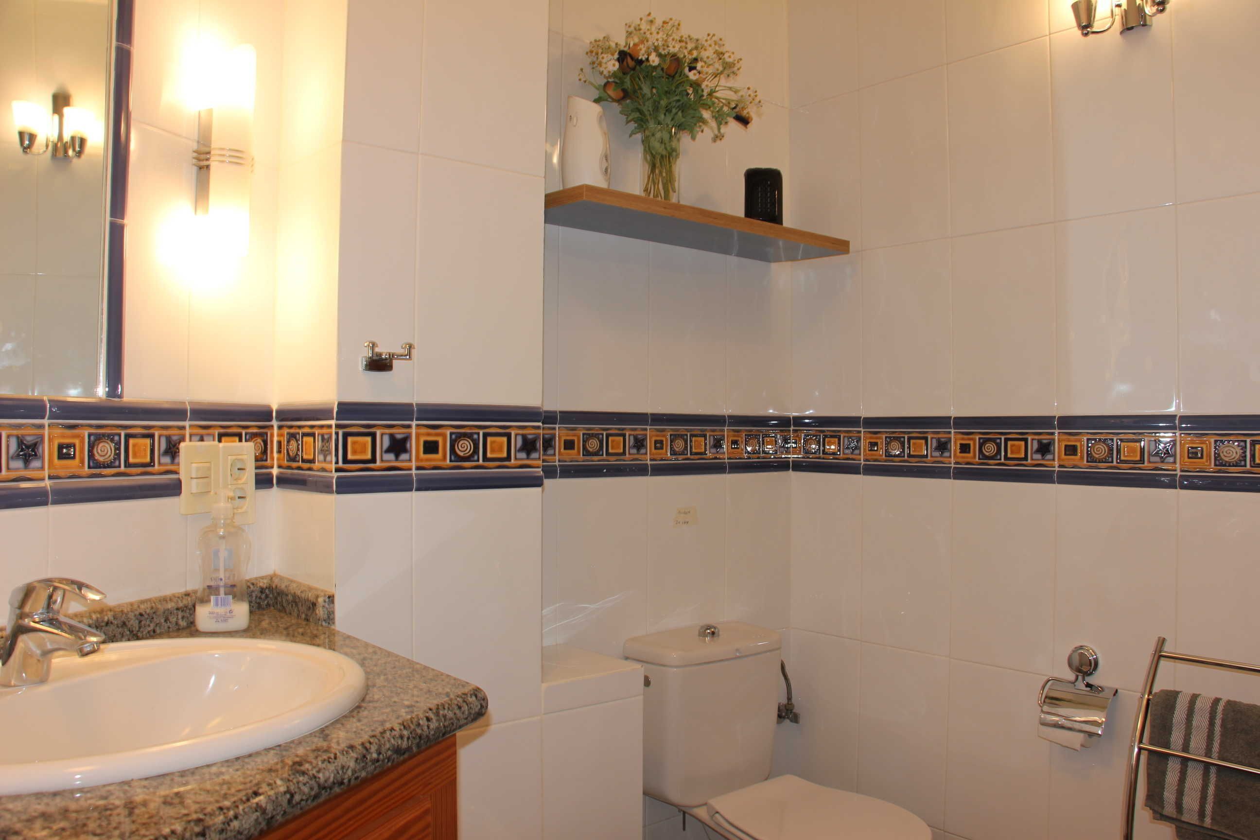 Een badkamer met een wastafel, toilet en handdoekhouder.
