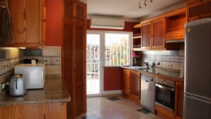Eine Küche mit Holzausstattung, einem Toaster, einem Kühlschrank und einem Geschirrspüler.