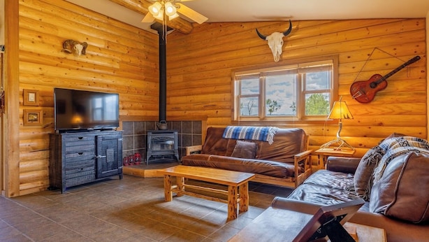 Een gezellig chaletinterieur met een open haard, houten meubels en een aan de muur bevestigde gitaar.