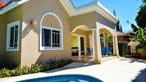 A house with a swimming pool, a covered patio, and a garden.