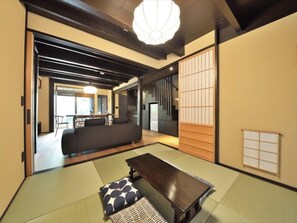 Een traditionele Japanse kamer met tatami vloerbedekking, een lage tafel, kussens en schuifdeuren.
