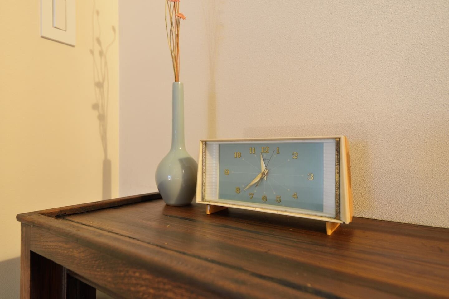 A wall clock with a blue face and gold frame on a wooden surface.
