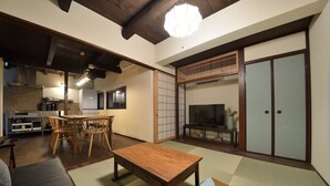 A traditional Japanese-style living room with tatami flooring, a low wooden table, and a TV on a wooden stand. - TAKEYA Gojo East  (竹屋五条東館) (Kyoto)