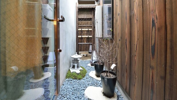A narrow corridor with a wooden fence, a stone lantern, and potted plants. - TAKEYA Gojo East  (竹屋五条東館) (Kyoto)