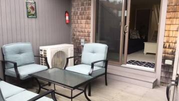 An outdoor patio with two light blue chairs and a glass-top table.
