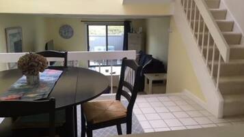 A dining area with a table, chairs, and a vase of flowers.
