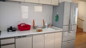 Una cocina moderna con un lavamanos, una cesta roja, un grifo y un refrigerador.