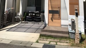 Una casa moderna de dos pisos con fachada blanca, una puerta de madera y un área de garaje techada.