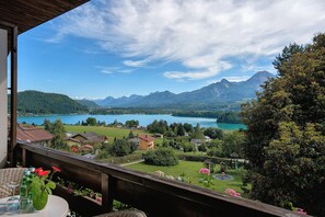 Un balcon avec vue sur un lac, des montagnes et un parc agrémenté d’un kiosque.