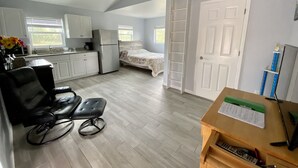A compact room with a kitchenette, a bed, a desk, and a ceiling fan.