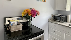 A kitchen with a microwave, a toaster, and a vase with flowers on the counter.