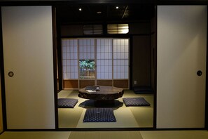 Une pièce de style japonais traditionnel, avec un sol recouvert de tatamis, une basse table en bois et des paravents en papier de riz (shoji).