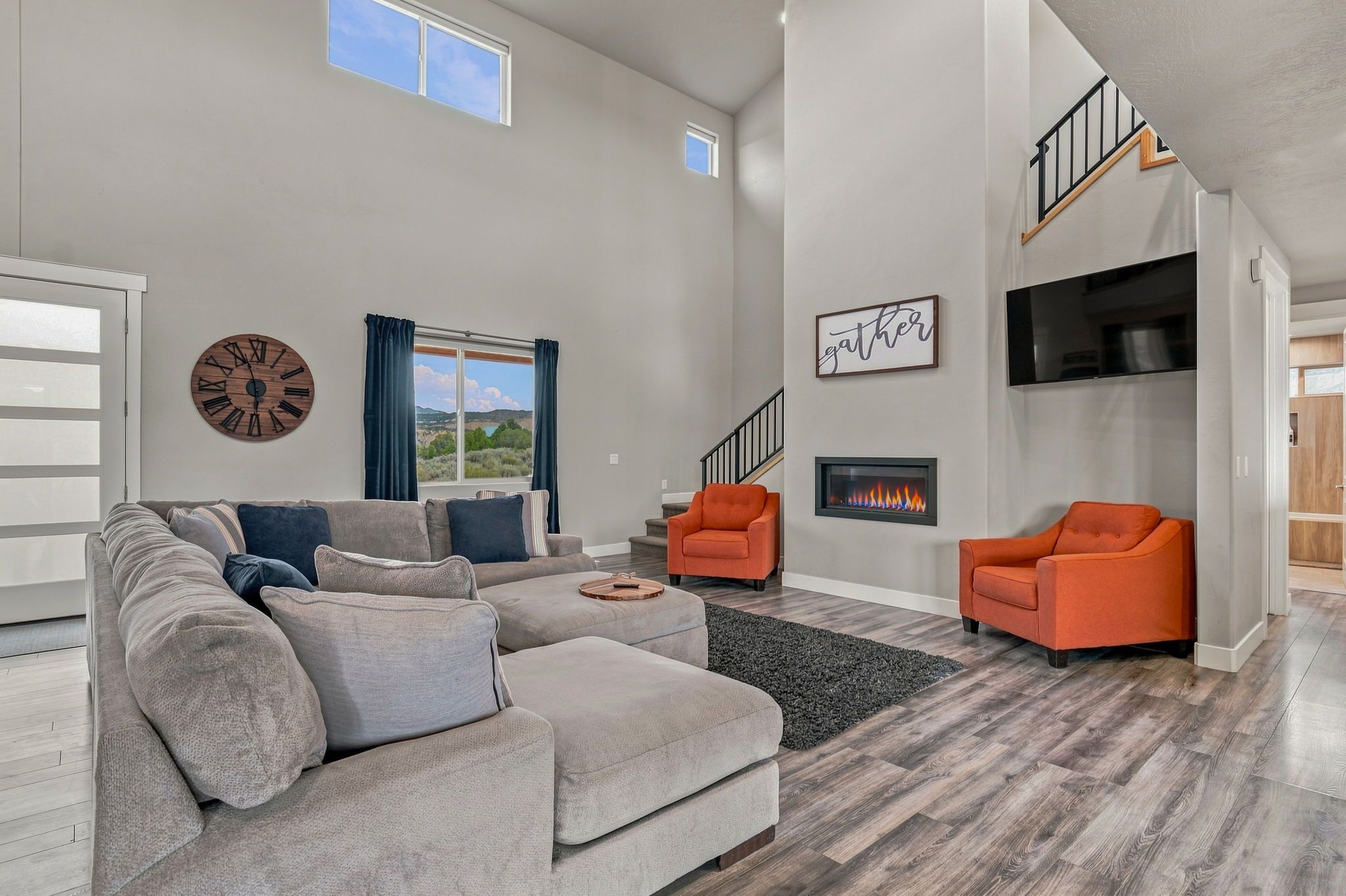 A spacious living room with a sectional sofa, two armchairs, a fireplace, and a view of the outdoors.