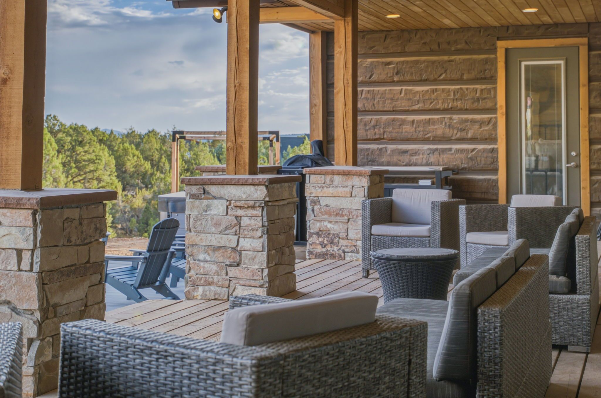 An outdoor patio with stone walls, wicker furniture, and a grill.