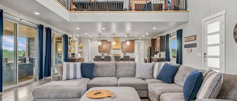 A spacious living room with a large sectional sofa, a dining area, and a kitchen.