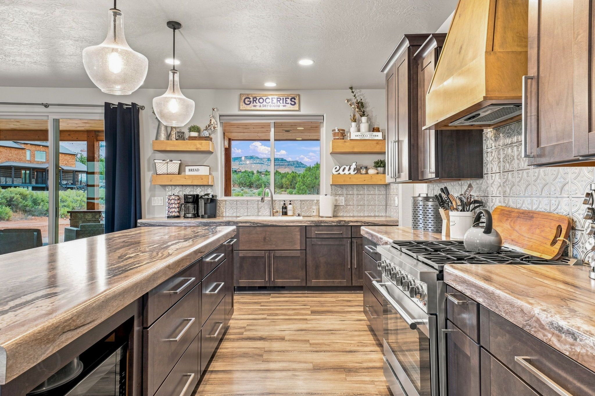 A modern kitchen with a large island, stainless steel appliances, and a view of the outdoors.