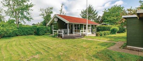 Ein kleines Haus mit rotem Dach, einer Veranda mit Stühlen und einer Satellitenschüssel.