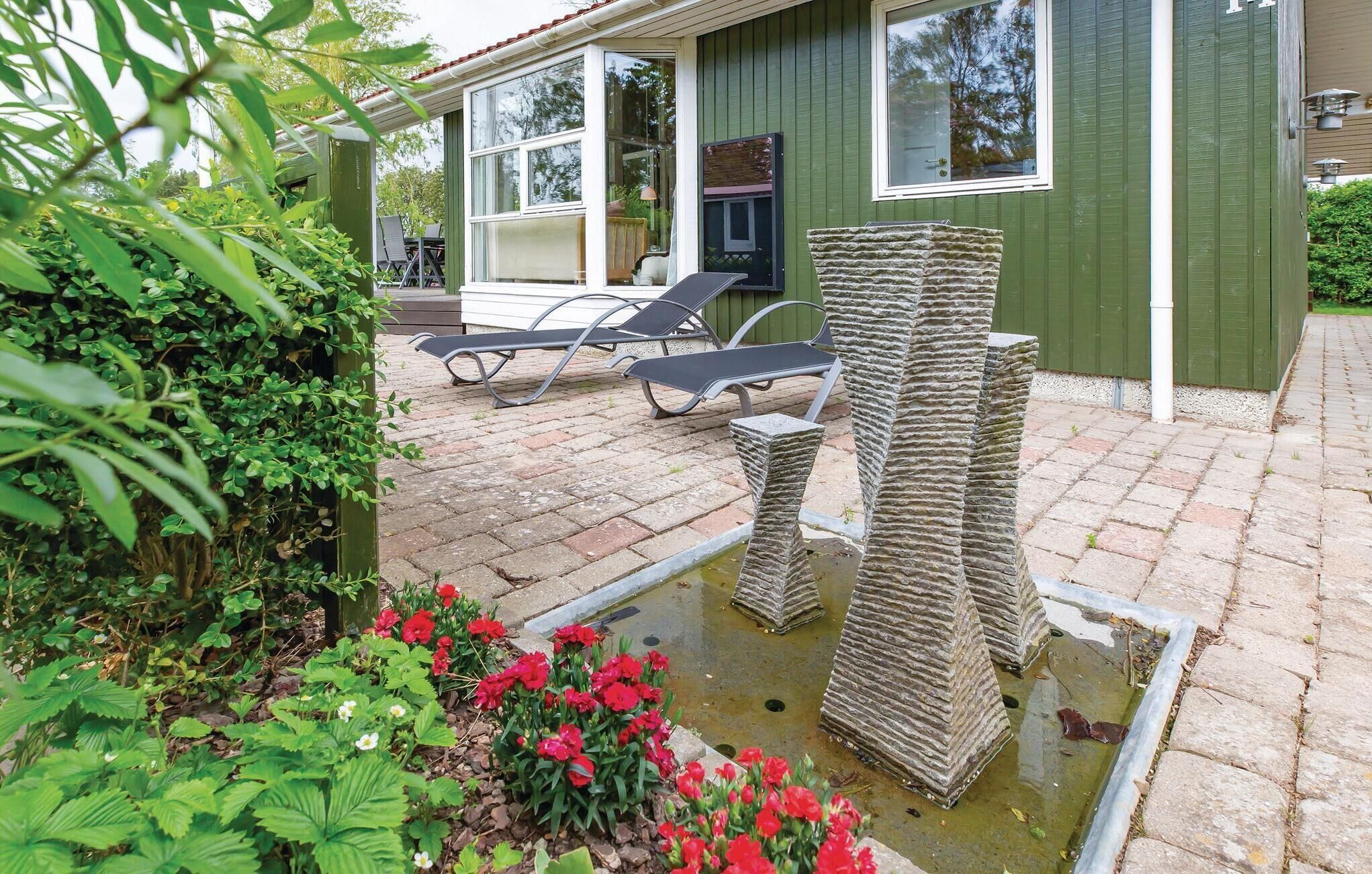 Een terras met een stenen fontein, een zwembad en ligbedden.