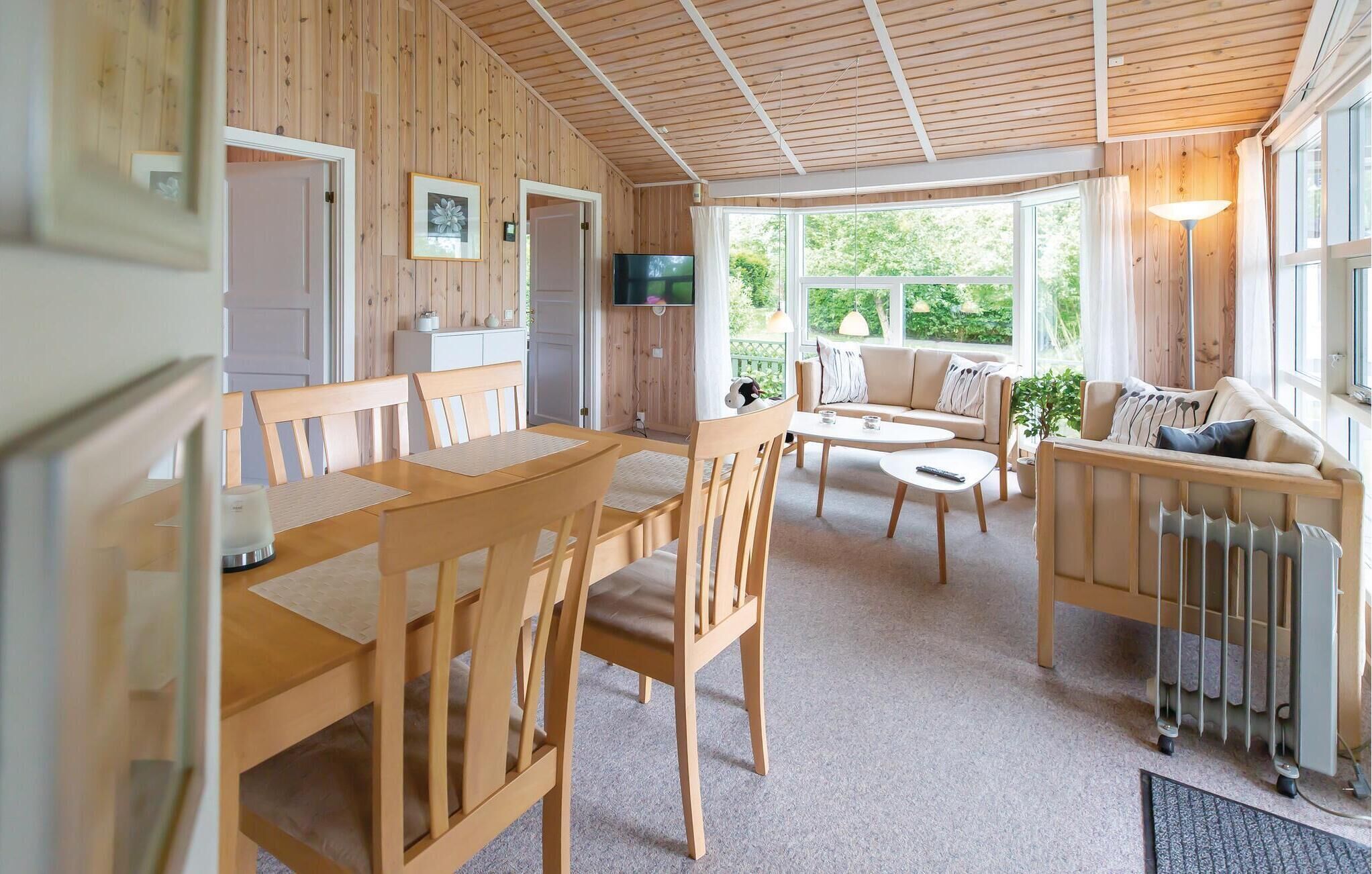 Een gezellig interieur van een chalet met een eethoek, een bank en een televisie.