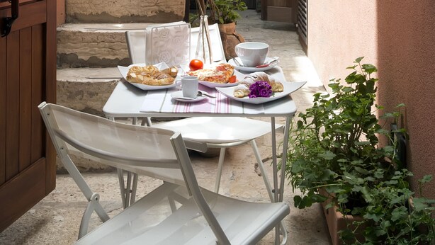 A narrow alleyway with a stone staircase leading to a building. There is a table with plates of food and a chair. - the flowery courtyard srl no12 (Trapani)