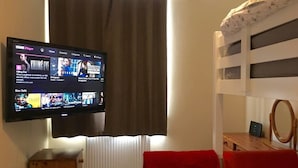 Une chambre à coucher avec un téléviseur fixé au mur, affichant l’interface d’un service de diffusion en continu.