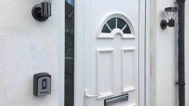 Une porte blanche avec un panneau de verre et une petite fenêtre au-dessus.