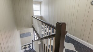 A staircase with white paneling and a black railing, leading to an upper floor. - Luxurious 1BR Located Near Downtown & Hospital (Winston-Salem)